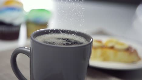 cristales de azúcar cayendo en una taza de café - cámara lenta