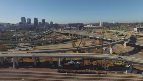 cars driving over busy downtown city overpass and equipment during on ramp construction project