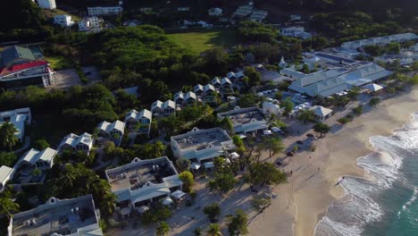 aerial pan around beachfront hotel property reveal to sunset behind sea cliff