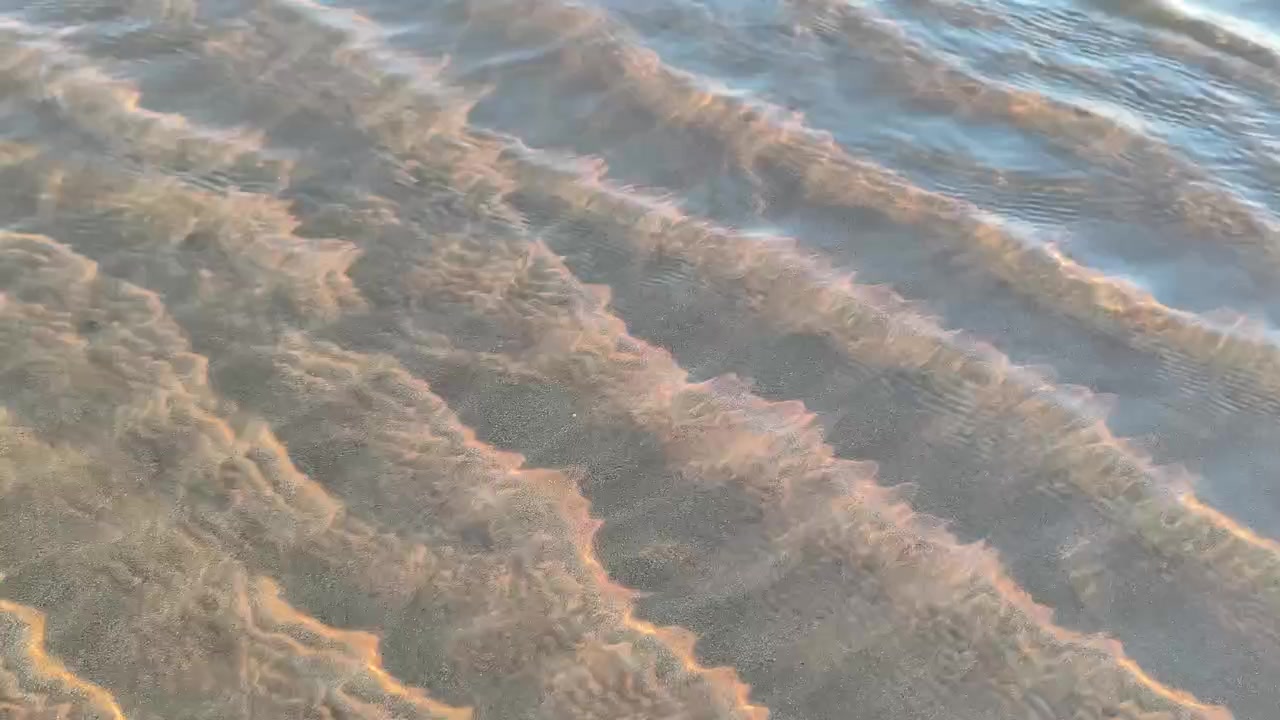 Clear Shallow Water Flowing Over Rippled Sand at Sunset