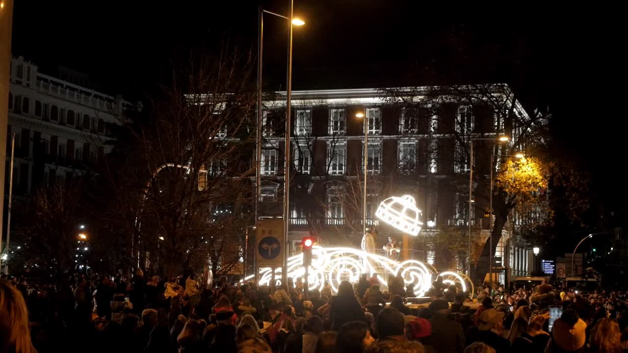 Nighttime Parade with Illuminated Float and Large Crowd
