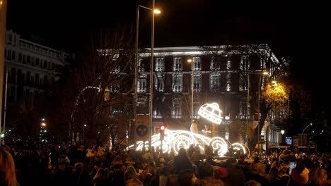 nighttime parade with illuminated float and large crowd