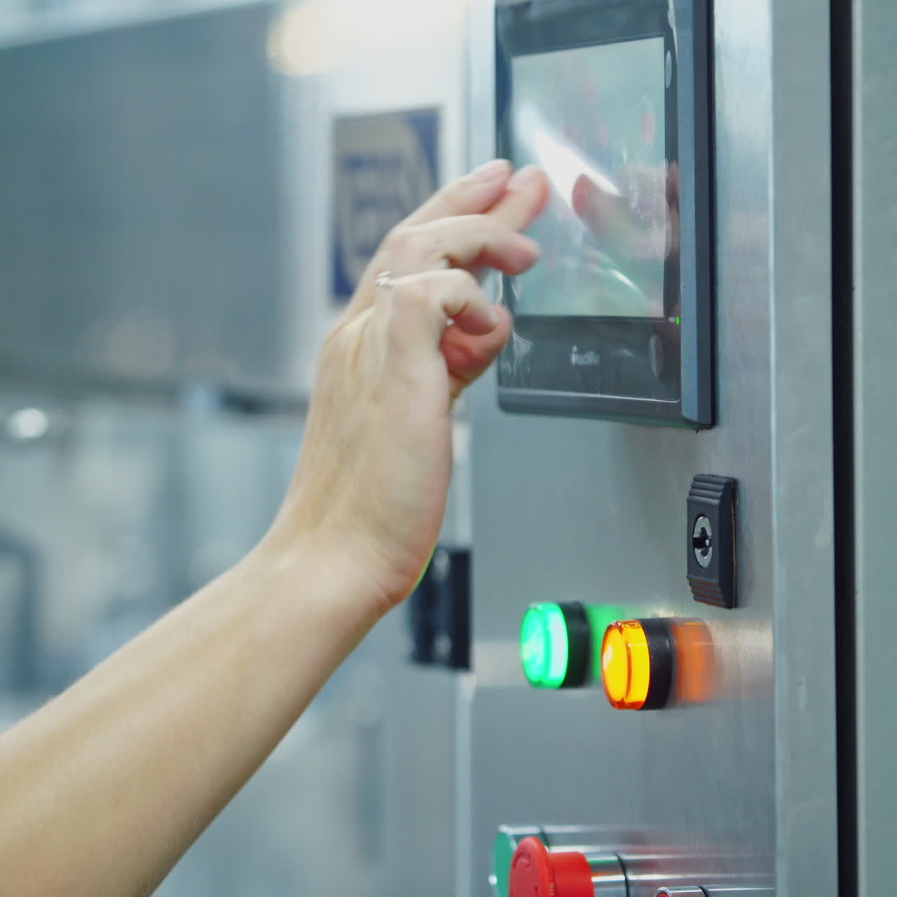 Woman turn on a mechanical machine for milk packaging into bottles. Automated equipment starts the process of bottling milk on a modernized dairy factory.