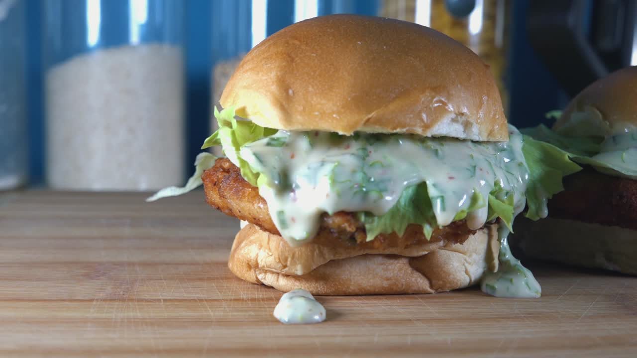 tiro de seguimiento en cámara lenta de crujientes deslizadores de pastel de pescado casero en una tabla de cortar de madera en la cocina