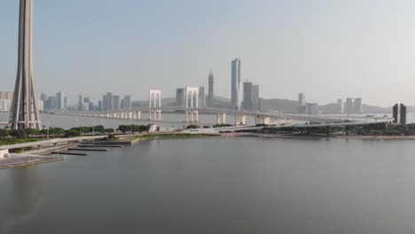 Drohne-Rückwärts-Zeigt-Eine-Aufnahme,-Die-Den-Verkehr-Auf-Der-Sai-Van-Brücke-Mit-Dem-Sockel-Des-Macau-Tower-Zeigt