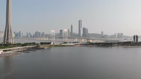 drone backwards reveal shot showing traffic on sai van bridge with base of macau tower