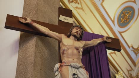 realistic statue of jesus crucified on a wooden cross inside a richly decorated church