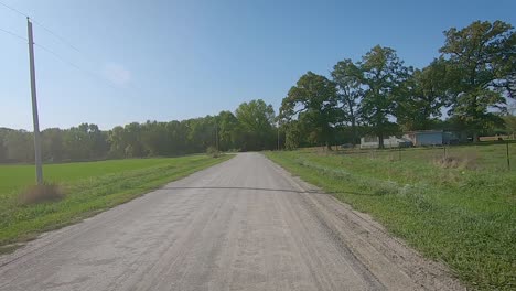 pov beim fahren um eine kurve auf einer schmalen schotterstraße im ländlichen iowa im spätsommer