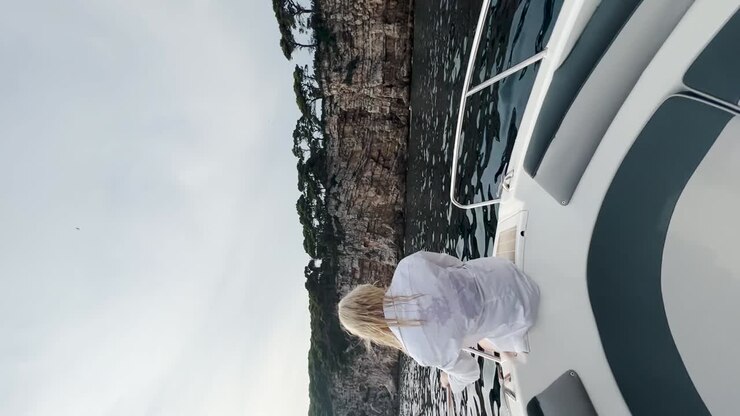 Giovane donna seduta sul ponte di una barca che si gode la vista del mare, Croazia.