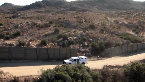 a vehicle travels up a road bordered by a tall fence