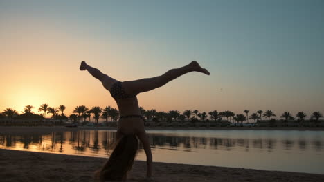 mujer joven sonriente mostrando rueda de carreta en la costa del mar a la hora de la puesta del sol.