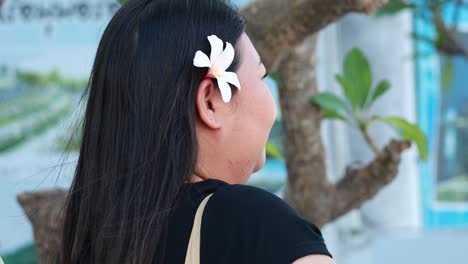 a woman places a flower in her hair