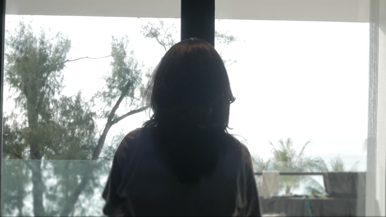 여름 방학 휴가 시간에 젊은 여성이 바다 전망을 감상할 수 있는 흰색 커튼을 엽니다