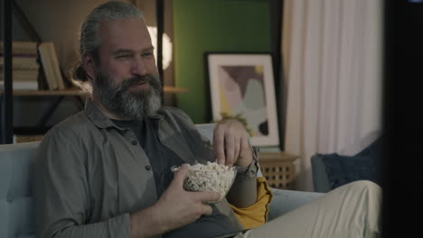 hombre viendo la tv con palomitas de maíz
