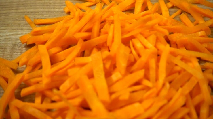 Sliced тАЛтАЛcarrots fall on a wooden board. Slow motion