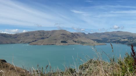 Extinct-volcano-provides-backdrop-to-boating-activity-on-calm-water-in-harbor---Gollans-Bay,-Banks-Peninsula