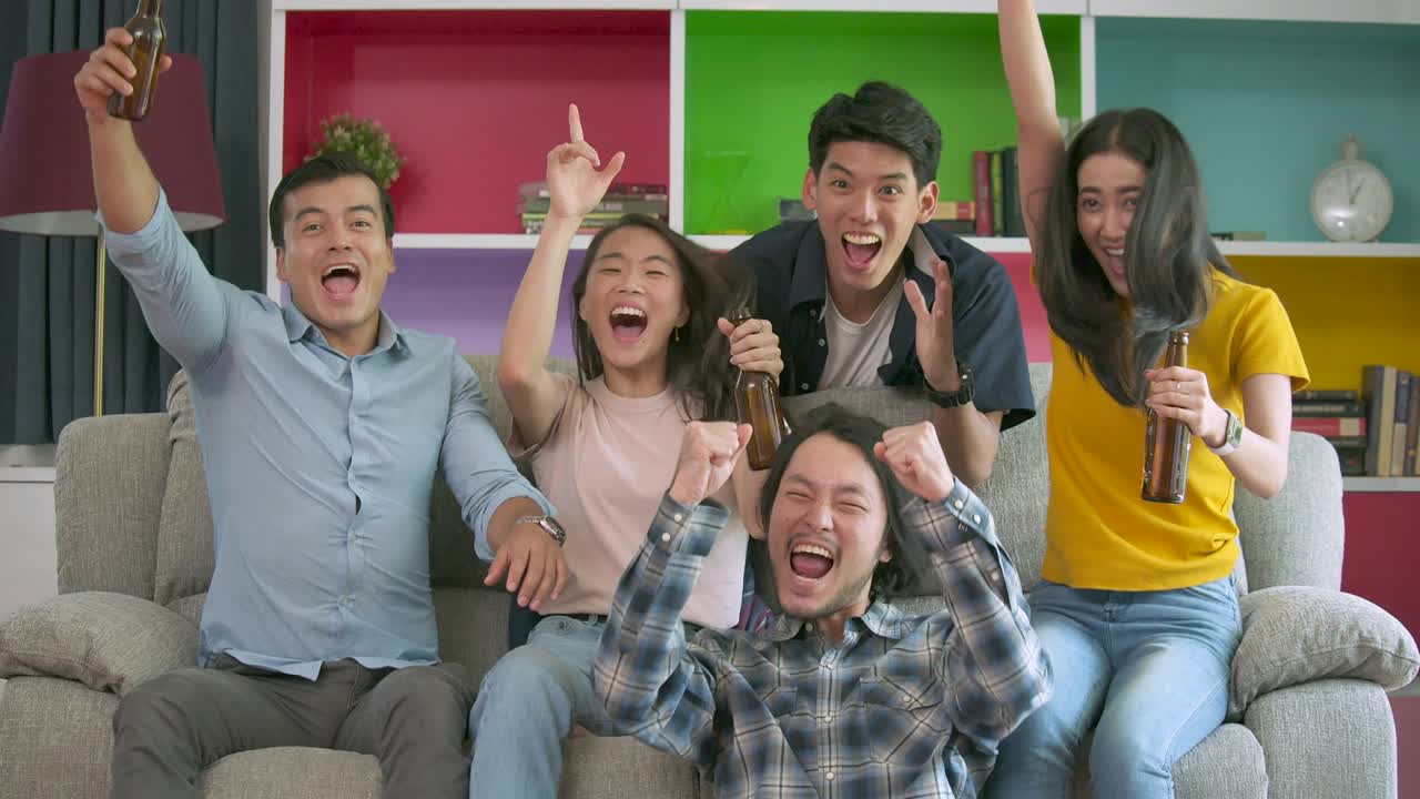 집에서 함께 tv에서 축구 경기를 보고 골을 축하하는 젊은 친구들의 느린 동작.