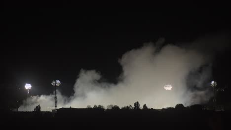 smoke rises above the football stadium at night, total, zoom out