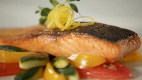 close-up shot of a perfectly cooked salmon fillet served with colorful vegetables and lemon zest