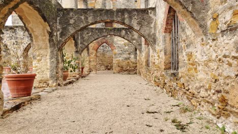 first person view walking through old mission arches, plant pots and colorful brick work and stone