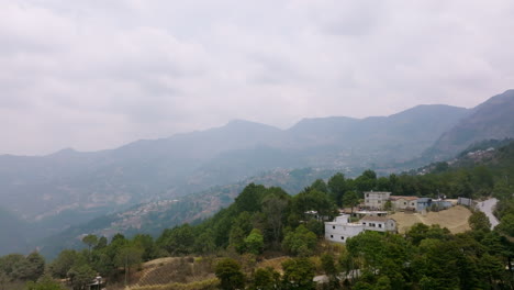 Left-to-right-aerial-dolly-of-some-houses-and-road-on-a-mountain-with-haze-in-the-air-in-Guatemala