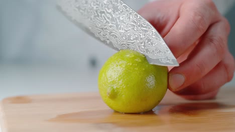 person cutting lime on wooden cutting board