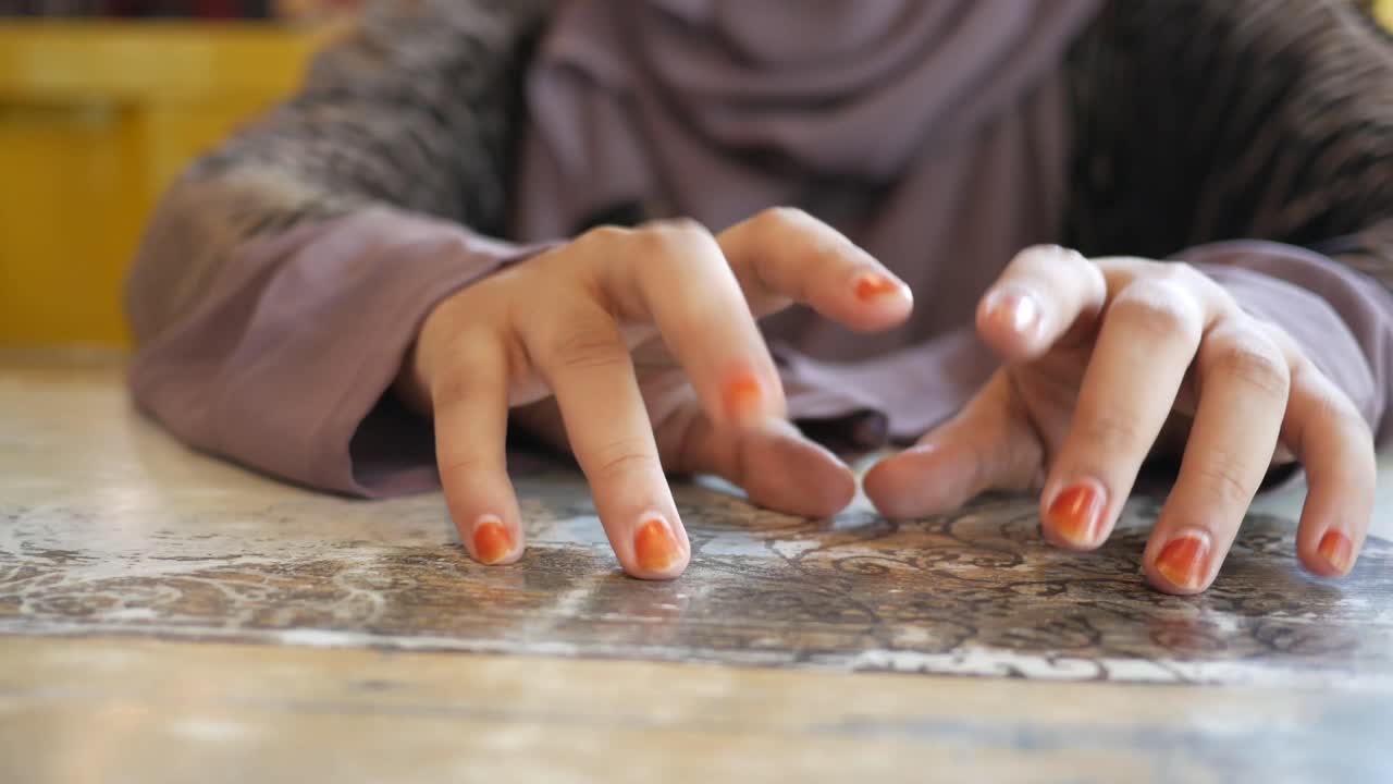 manos de mujer con uñas de naranja en una mesa