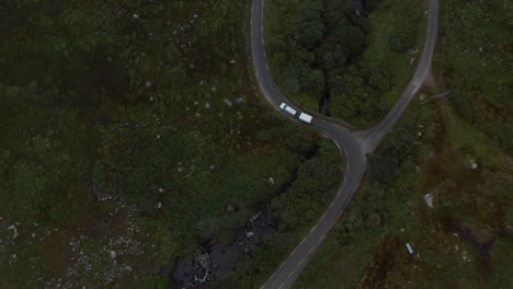 High-angle-view-of-vehicle-passing-through-curves-on-narrow-road-in-countryside.-Birds-eye-shot-of-van-with-trailer.-Ireland