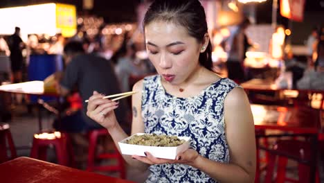 mujer asiática comiendo arroz en el mercado nocturno