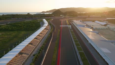 the tranquil mandalika motorbike race circuit at sunrise: empty tracks stretching straight through coastal scenery, awaiting the roar of engines and the thrill of competition