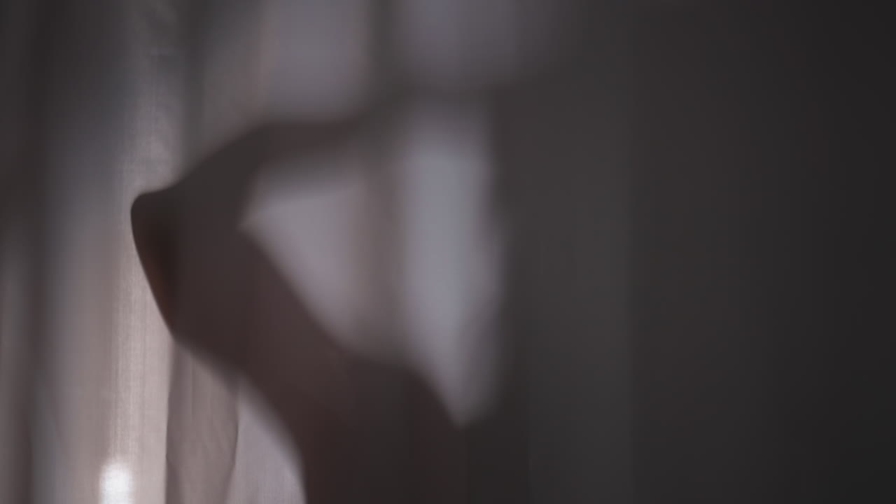 커튼 뒤에서 샤워하는 여성의 실루. 여성은 집 화장실에서 물 스프레이 아래에서 머리를 는다. 여성은 일상적인 위생 절차를 즐긴다.