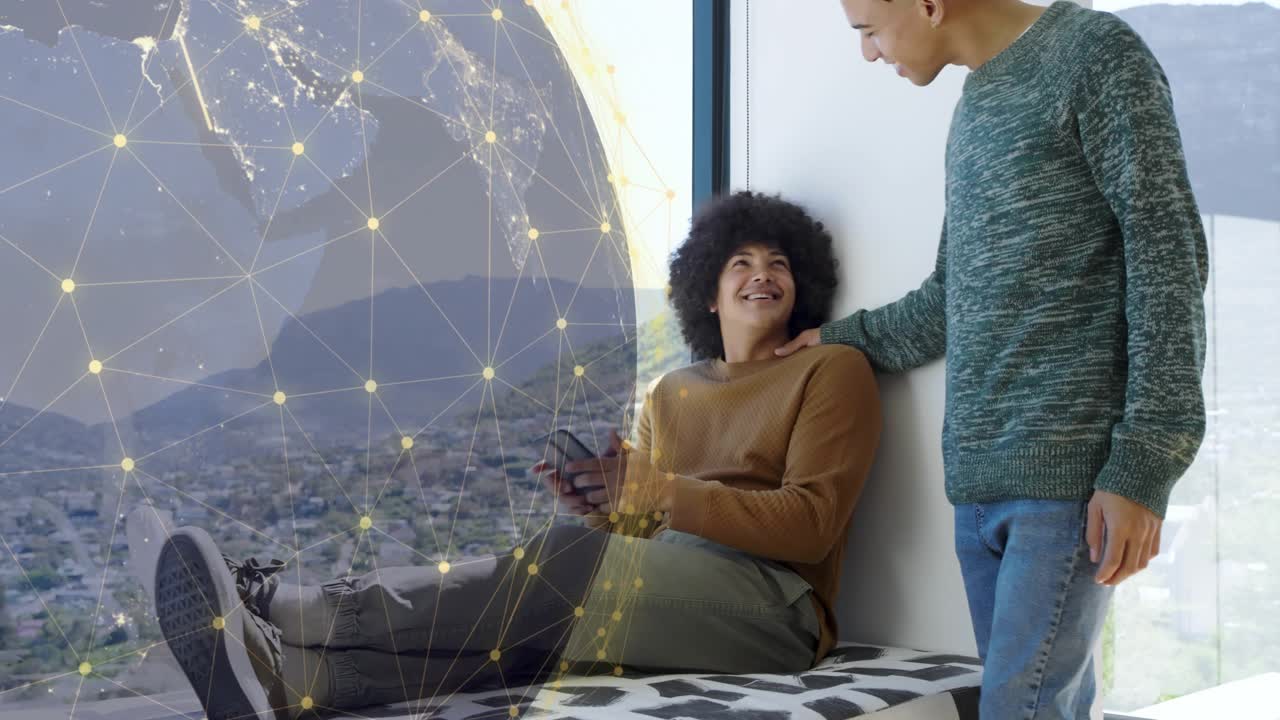 Seated man swiping phone initiating tech globe overlay friend stopping to touch shoulder connecting