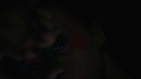 retrato de cerca de una mujer hermosa con una pintura de rostro colorida bailando arte corporal multicolor exótico con destellos de luz