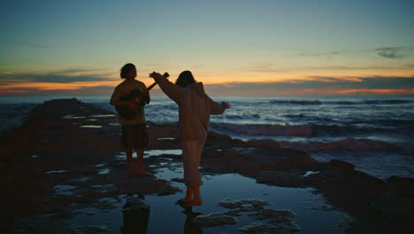 pareja tocando la guitarra en la playa al atardecer