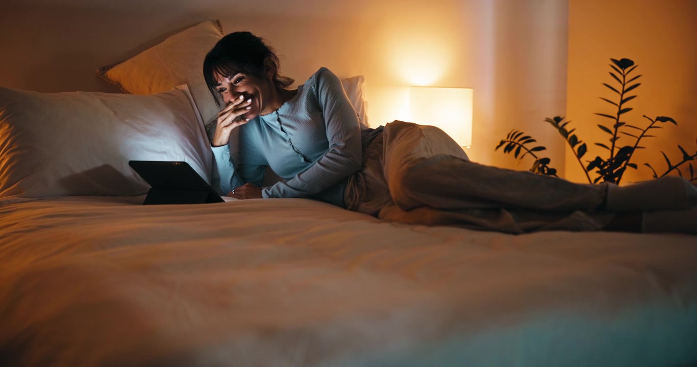 Donna Felice Guarda Contenuti su Tablet a Letto di Notte
