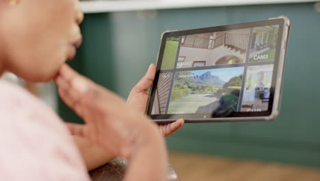 african american woman reviews cctv security footage on a tablet at home