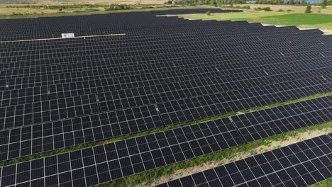 Aerial-view-of-photovoltaic-solar-pane-base-station-farm-drone-fly-above-revealing-wind-turbine-at-distance-renewable-green-energy