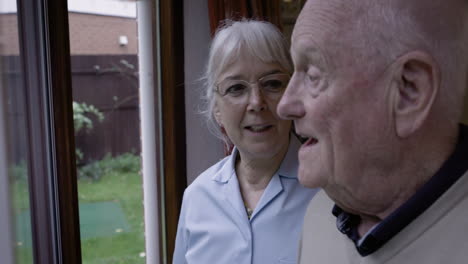 elderly man and caregiver looking out the window