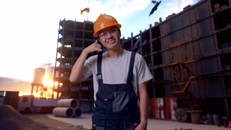 hombre asiático trabajador haciendo llamarme gesto a la cámara en el sitio de construcción