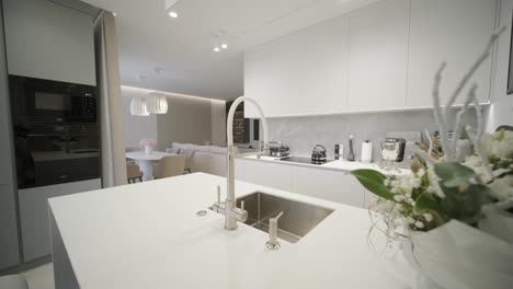 a luxurious kitchen with a large island, gold faucet and sputnik chandelier, stainless steel appliances, and white marble countertops.