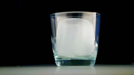 Glass-with-ice-and-water-against-black-background-4k