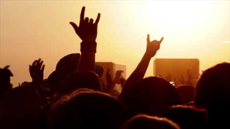 unrecognizable people holding hands up during concert