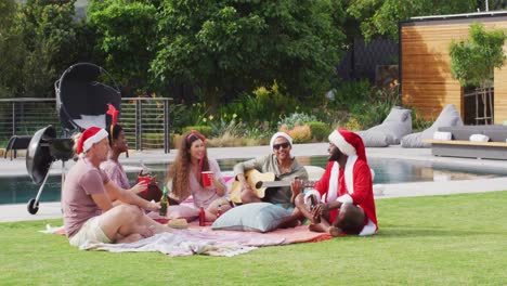 Feliz-Grupo-De-Amigos-Diversos-Tocando-La-Guitarra-En-La-Fiesta-De-Navidad-En-El-Jardín