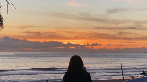 cámara lenta de personas en la playa de carcavelos, las olas se forman y rompen lentamente, hermoso océano atlántico, puesta de sol de color amarillo intenso sobre los reflejos del agua, portugal