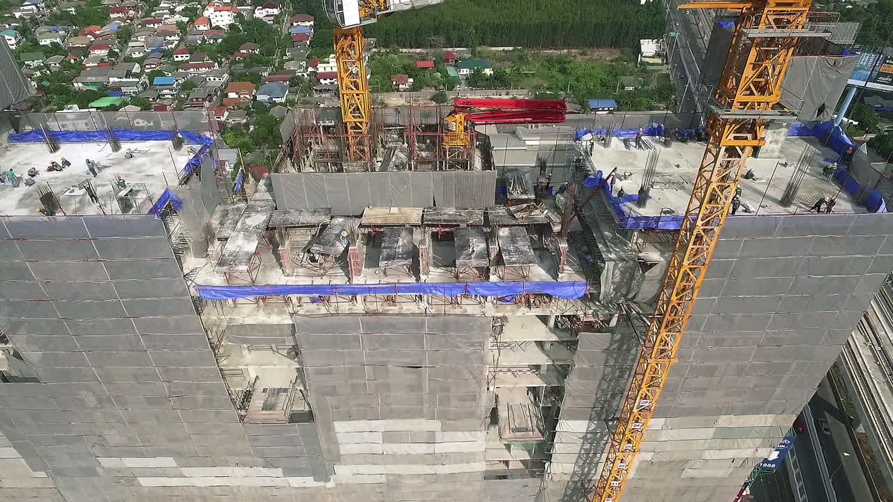 vista aérea de un moderno edificio de gran altura en construcción en el ajetreado distrito de negocios del centro de la ciudad con trabajadores, andamios y grúas
