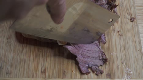 slicing lamb roast on the bone with cleaver, juicy, dolly shot