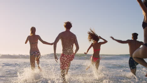 Diverse-Group-of-friends-swimming-in-the-sea-at-sunset