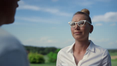 mujer discutiendo ocio de golf en campo de campo soleado. jugador de deporte hablando al aire libre.