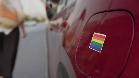 applying pride sticker to red car