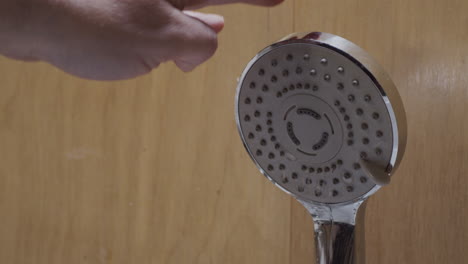 los grifos de mano obstruyen el cabezal de la ducha mientras gotea el agua